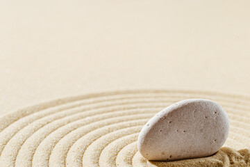 Fototapeta na wymiar Aesthetic minimal background with zen stone on sand. Japanese Zen Garden with concentric circles around stone cairn.