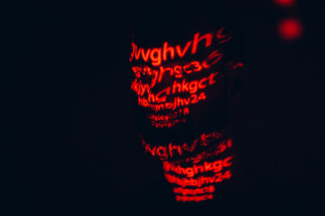 Young man with red letters on his face in the dark