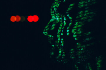 Young man with geen abstract letters on his face in the dark