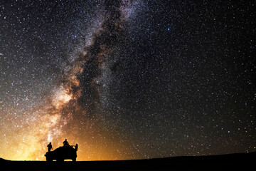 
The silhouette of the off road cars and hikers stand on the hill of the beautiful  starry night with bright milkyway galaxy. Night landscape. Astronomical background.