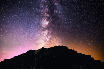 Beautiful night landscape, snow-capped mountains and hill, starry sky with bright milky way galaxy. Night landscape. Astronomical background, night scene.