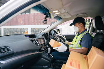 Naklejka premium A delivery man using a credit card reader. In the van with parcels on the outside of the warehouse. Delivery