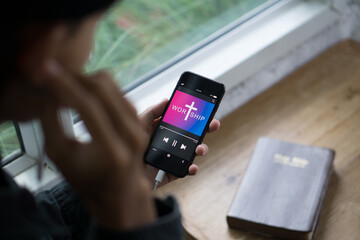 Christian man holding mobile phone praying worship to GOD with church online Sunday Live Church with the bible.Quarantine from Covid-19 Coronavirus pandemic.