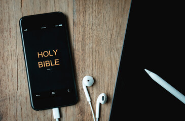 open bible with phone and headphones,Concept listen the words of God.Bible, phone,laptop and...