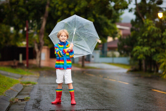 Child playing in autumn rain. Kid with umbrella.