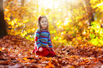 Child in fall park. Kid with autumn leaves.