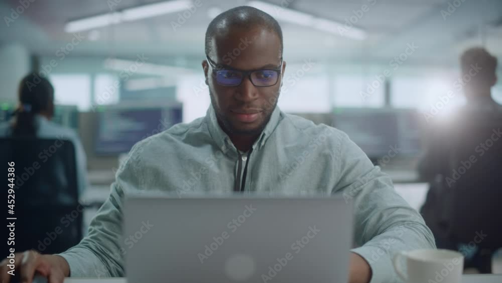 Poster Office: Portrait of Confident IT Programmer Wearing Headphones Working on Computer, Looking at Camera and Smiling. Black Male Software Engineer Developing Innovative App, Program, Video Game. Zoom In