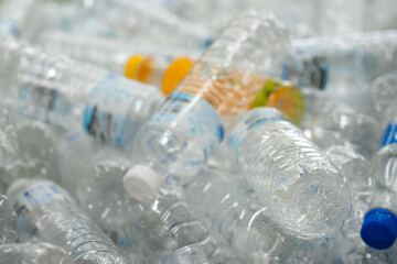 Plastic drinking water bottles are grouped for recycling process. Waste management for green environmental concept. Close-up and selective focus on foreground.