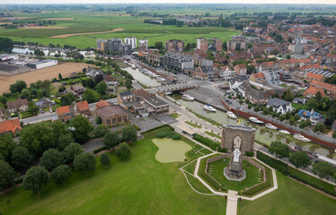 Fototapeta na wymiar Diksmuide, Flanders, Belgium - August 3, 2021: IJzertoren domain. Aerial landscape showing agriculture, large part of town, the IJzer river with boats, and the Pax gate with crypt.