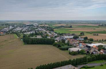 Diksmuide, Flanders, Belgium - August 3, 2021: Aerial view on wide agricultural landscape NW of Ijzertoren under Light blue sky. Industry zone and church of Kaaskerke village along N35.