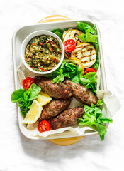 Roasted meat kebab , grilled vegetables sauce, zucchini, flatbread, green salad - delicious mediterranean style lunch on a light background, top view