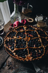 Rustic peach-blueberry-ricotta spelt pie on old wooden table served with coffee and fruits.