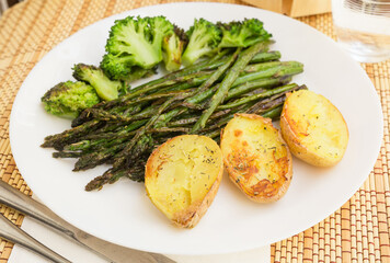 lean dish of cooked fried inflorescences of broccoli, asparagus growth and baked potatoes and Provencal herbs