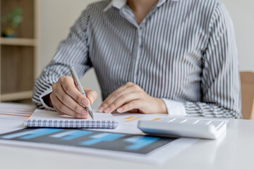 A businesswoman is taking notes in a notebook, she checks company financial documents and she takes corrective reports to the finance manager for correction. Finance concept.