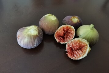 figs on a wooden table ripe whole and cut ripe in brown background
