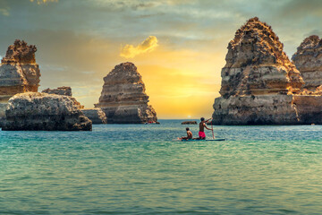 Beautiful beach at sunset with boats, kayaks and stand up boards. Dona Ana beach in the Algarve -...