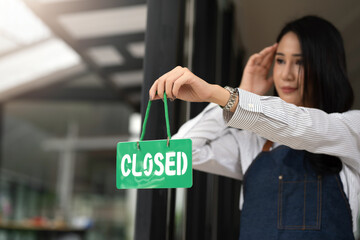 Woman small business owner holding a closed sign at a café.