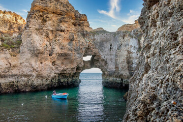 Blue boat on a rocky cavern at Ponta da Piedade, Lagos, one of the most beautiful areas of the beaches in Algarve - Portugal. Cliffs and rocky caverns in the Algarve - Portugal