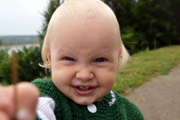 Caucasian toddler happily smiles and looks straight, close up