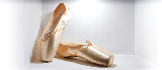 Close-up new beige pink ballerina pointe shoes in concrete wall niche,light background,side...