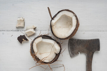 A coconut is chopped in half on a light wooden table. Top view