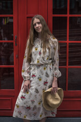 Obraz premium Beautiful caucasian young woman in dress standing on the street in London and smiling. Long straight blond hair. Red english phone booth