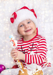 Little kid wearing Santa Claus hat prepares gingerbread