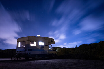 van life concept. long exposure of recreational vehicle, also called camper, parked at night under...