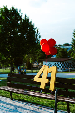 Decorative numbers and balloons on bench in park