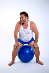 Fototapeta na wymiar Funny fat man training with a fitness ball. Adult guy on a white background. Copy space. Active sports with a diet.