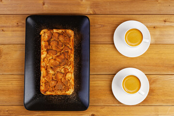 French apple cake. Homemade apple clafouti and two cups of coffee on wooden table. Top view.