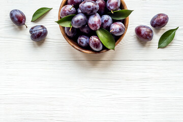 Purple plums with leaves top view. Food fruits background