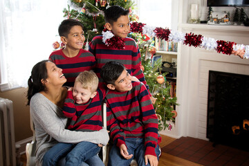 Funny indoor casual Christmas portrait of five siblings in matching clothing laughing and having...