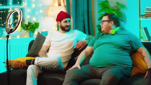 Good looking man obese and other guy at home on the sofa they have a live stream using a smartphone to recording and light ring