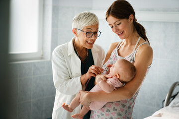 Mother holding baby for pediatrician doctor to examine