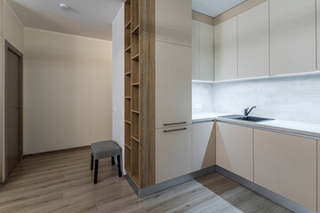 Modern interior. Kitchen in apartment. Beige cabinets. Wooden shelves.