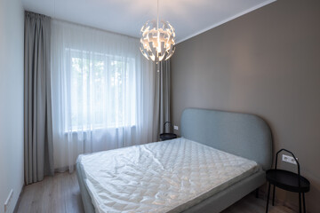 Modern interior. Bedroom in apartment. Beige wall. New mattress on bed