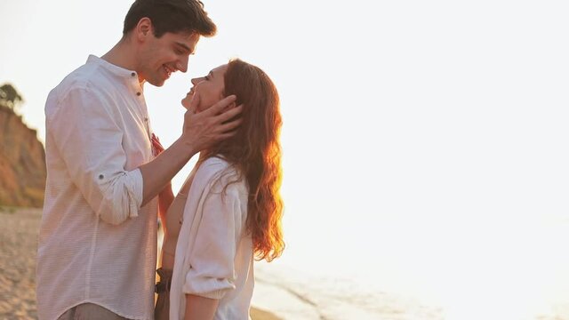 Charming romantic young couple two friends family man woman 20s in white clothes hug going to kiss other together together at sunrise over sea beach ocean outdoor seaside in summer day sunset evening