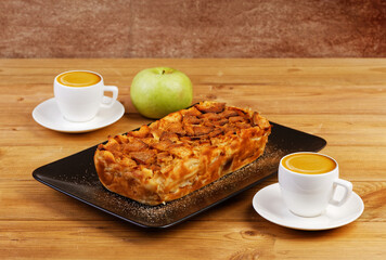 French apple cake. Homemade apple clafouti and two cups of coffee on wooden table. Angle view.
