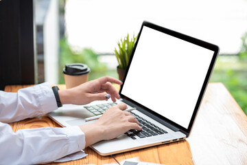 Close-up of a businesswoman hand holding a pen working using a laptop keyboard blank white screen at the office. Mock up.
