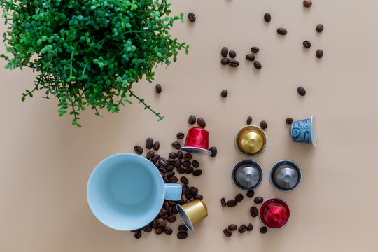 Coffeebreak With A Cup Of Coffee, Capsule, Coffeebeans And Green Plant On Beige Background