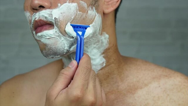 The guy shaving his beard on gray background