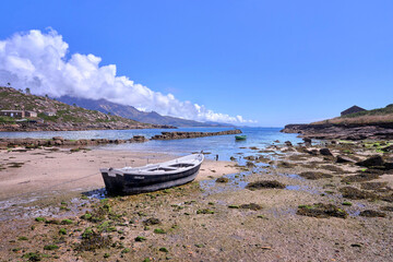 Fototapeta premium Low tide with a traditional fishing rowboat in the Galician coast, Northern Spain.