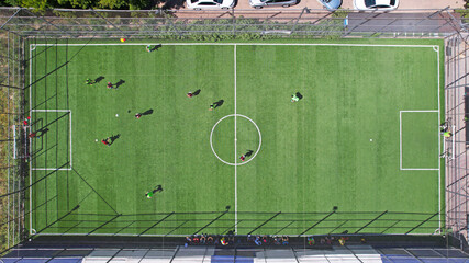 Two teams of guys are playing football on the field. Top view from the drone on the ball and...