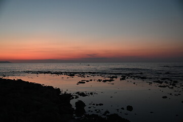 Sunset in Crete Greece, water, rocky shores, and pastel clouds