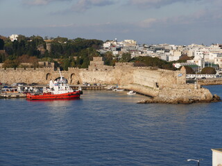 Fototapeta na wymiar Tugboat in the Embaria port of Rhodes Town, Rhodes, Greece, on the headland of the Nailac Tower, on the right in the picture the Nea Agora market hall