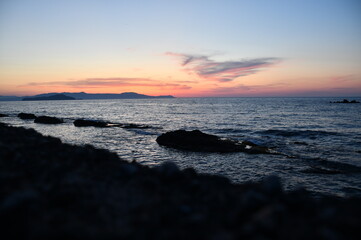 Sunset in Crete Greece, water, rocky shores, and pastel clouds