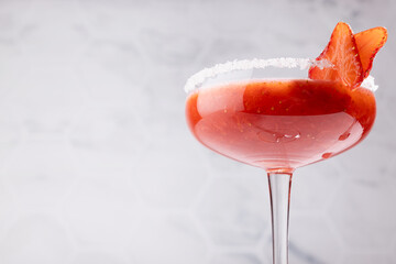 Fresh strawberry margarita cocktail in high glass goblet with sugar rim in soft light white...