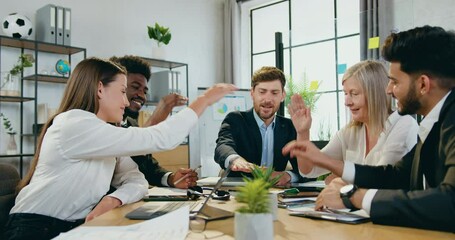 Good-looking satisfied confident skilled mixed race business team putting their hands on hands on top of each other during joint meeting in boardroom