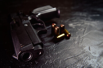 Black gun and bullets on table. Firearms on concrete background. Weapons and ammunition. Concept of crime and physical evidence. Pistol for defense or attack.